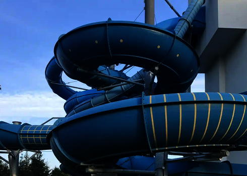 Blick von unten auf die blaue Family Twister Rutsche mit Stützen und Verstrebungen.