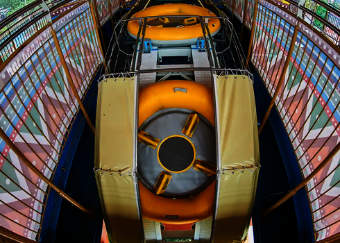 Two yellow slide rafts are located next to each other at the entry point of the raft conveyor.