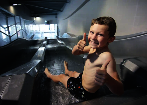 Kind zeigt Daumen hoch beim Start auf der Multilane im Hallenbad.