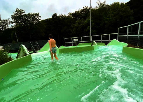 Ein Mann läuft durch das flache Wasser eines Wildwasserfluss-Abschnitts.