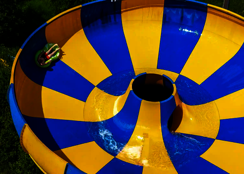 Gelb blaue Raft Bowl Reifenrutsche, Person rutscht auf grünem Rutschreifen.