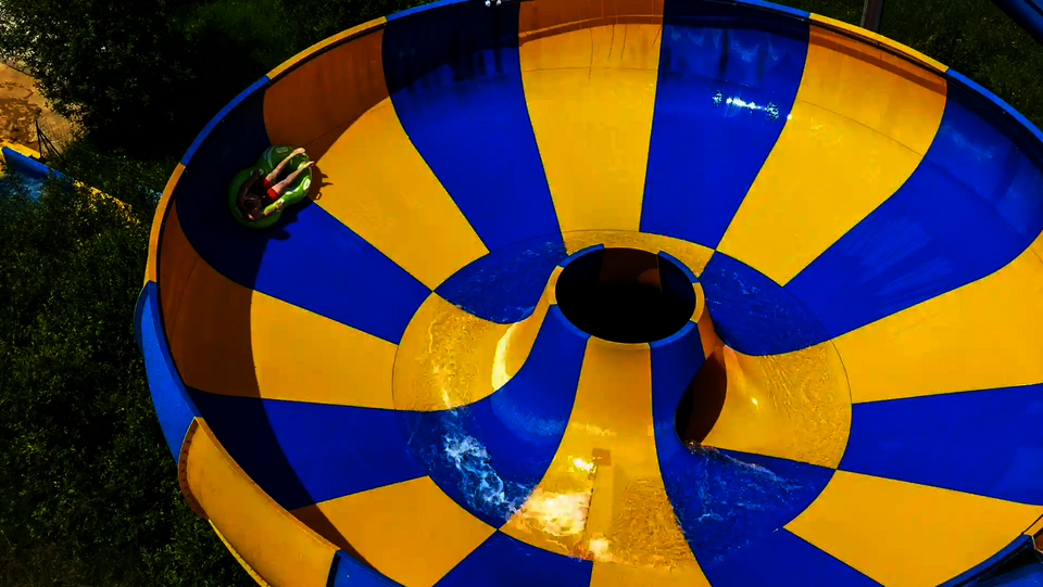 Gelb blaue Raft Bowl Reifenrutsche, Person rutscht auf grünem Rutschreifen.