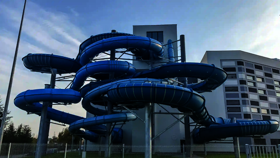 Viele blaue ineinander gewundene Wasserrutschen außerhalb eines Gebäudes.