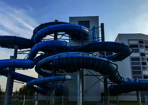 Viele blaue ineinander gewundene Wasserrutschen außerhalb eines Gebäudes.