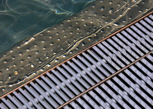 Detailed view of a stainless steel basin with water and drain grate at the edge of the run-out area.