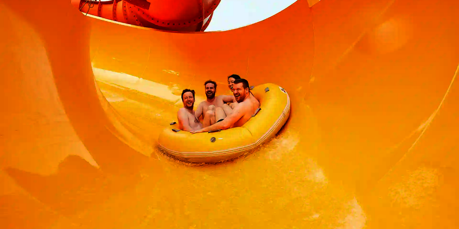 Vier Personen fahren gemeinsam im gelben Rundreifen durch den gelben Trichter der Rutsche RR2700.