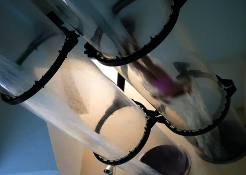 Eine Person rutscht kopfüber durch mehrere übereinander angeordnete transparente Acryl-Teile.