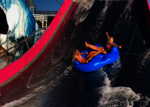 Zwei Frauen rutschen mit einem blauen Doppelreifen die Sidewinder hinunter.