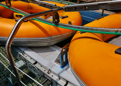 Close-up of yellow slide rafts on the conveyor belt of the raft conveyor with retaining brackets.