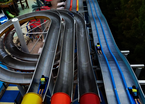 Blick von oben auf spiralförmig verlaufende Bahnen einer bunten Matracer Wasserrutsche.