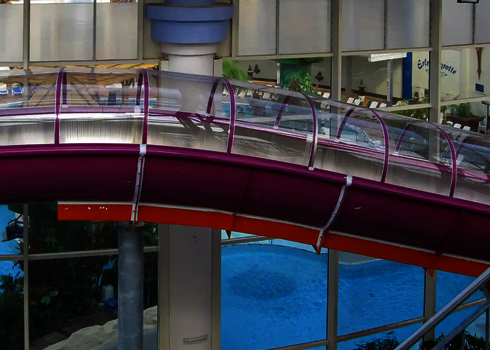 Ein violett-orangefarbener Speed Blaster-Kanal führt durch den Innenbereich eines Schwimmbads.