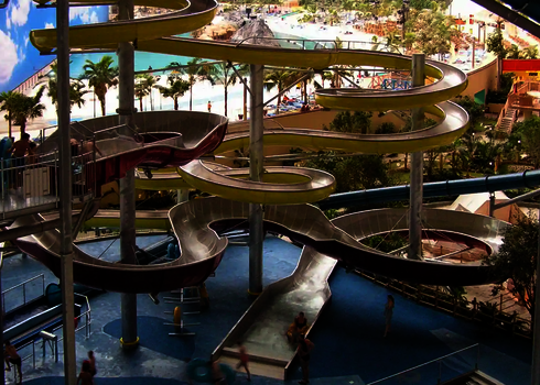 Rutschen in gelb, rot und blau in einem Indoor-Wasserpark in tropischer Atmosphäre.