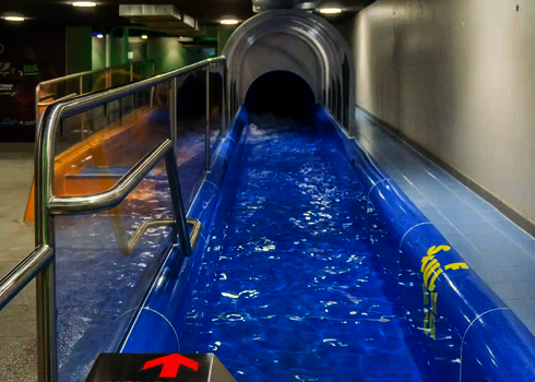 Blue slide with transparent tunnel and shiny water surface.
