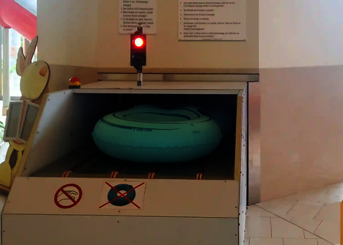 Light blue slide raft is automatically pulled in by the raft conveyor in indoor areas.