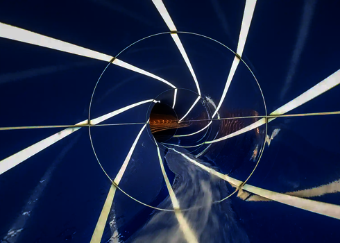 Innenansicht einer blauen Röhrenrutsche mit Tageslichteffekten in Form von Streifen.