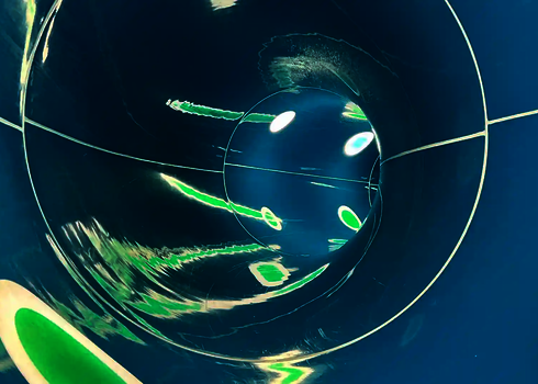 Innenansicht einer Wasserrutsche mit Tageslichteffekten in Form von Streifen und Punkten.