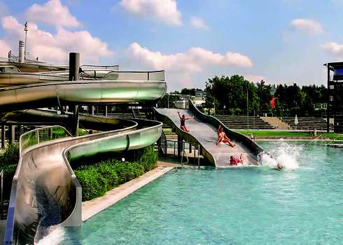 Three slides end side by side in a large outdoor pool, where children slide into the water.