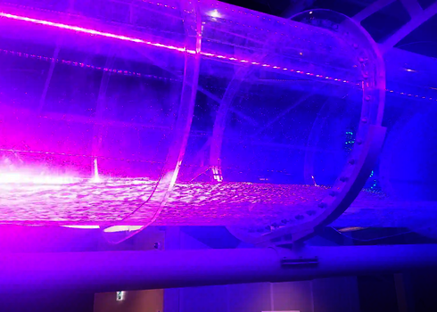 Ein Acryl-Element einer Wasserrutsche wird von intensiver pink-violetter Beleuchtung erhellt.