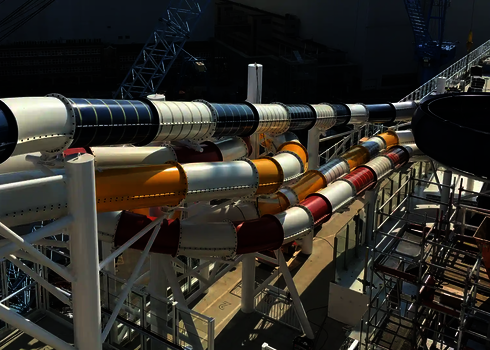 Mehrere bunte Wasserrutschen verlaufen auf einem Schiff, das sich im Bau befindet.