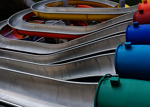 Verschlungene Edelstahlbahnen der Wasserrutsche Matracer mit bunten Röhrenstarts in mehreren Farben.