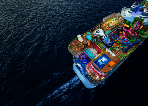 Vogelperspektive auf ein Kreuzfahrtschiff auf dem Ozean mit riesigem bunten Wasserrutschen-Komplex.