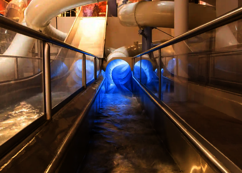 Auslauf mit Sicht auf blau beleuchteten Rutschenausgang im Hintergrund.