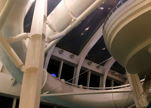 Eine weiße Röhrenrutsche in einem Hallenbad, draußen ist es dunkel.