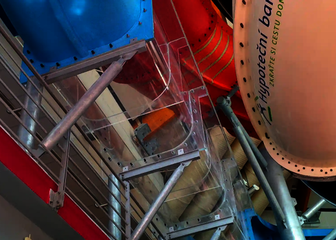 Eckiges Acrylrutschenstück mit Metallhalterung in einem bunten Indoor-Rutschenbereich.