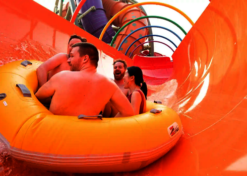 Vier Personen gleiten rückwärts sitzend durch den orangenen Tunnel mit bunten Ringen der RR2700.