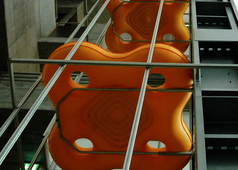 Two orange four-person slide rafts are transported vertically upwards using the raft conveyor.