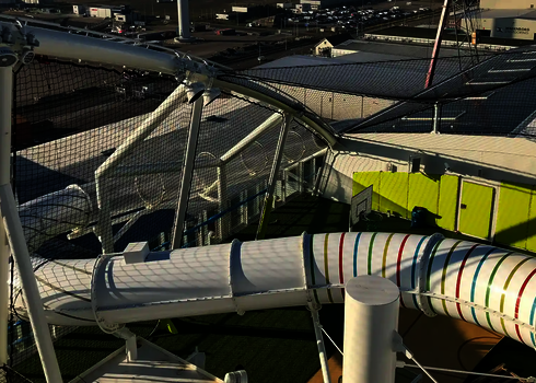 Weiße Wasserrutsche mit bunten Streifen auf grünem Boden.