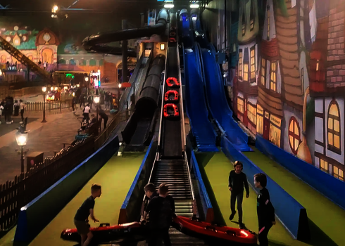 Indoor-Spielplatz mit spielen Kindern vor einer Harakiri Wasserrutsche.