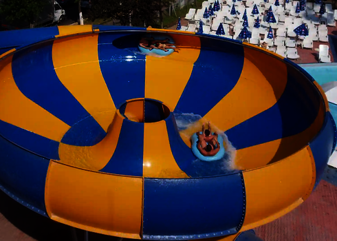 Raft Bowl mit mehreren Rutschenden, im Hintergrund weiße Liegestühle mit Sonnenschirmen.