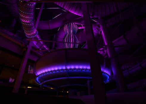 Innenaufnahme eines Hallenbads und einer Body Bowl in violetten Licht.