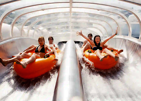 Zwei Teams rutschen auf zwei parallel verlaufenden Bahnen auf orangenen Reifen die Raft Racer Wasserrutsche hinab.