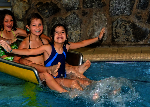 Kinder sitzen lachend auf einer gelben WR560 Kinderwasserrutsche.