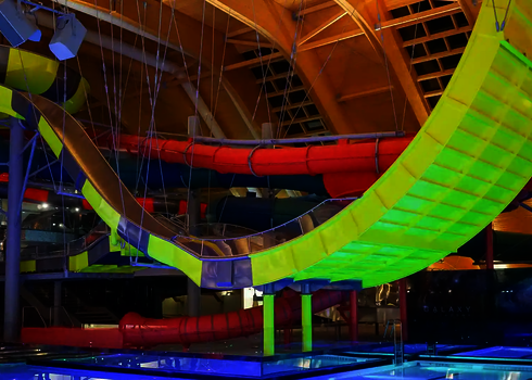 Die Reifenrutsche Boomerang verläuft über dem Wasserbecken mit bunter Röhrenrutsche im Hintergrund.