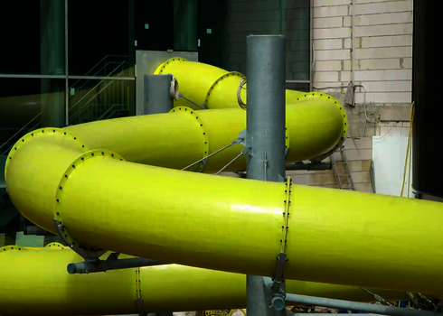 Eine gelbe RR1200 Wasserrutsche die in ein Gebäude verläuft.