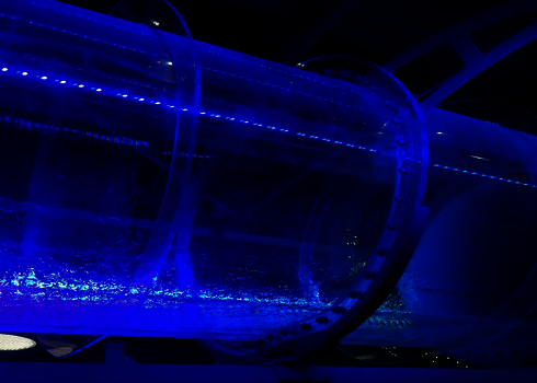 Blau beleuchtete Acryl-Wasserrutsche mit fließendem Wasser in einer Halle.