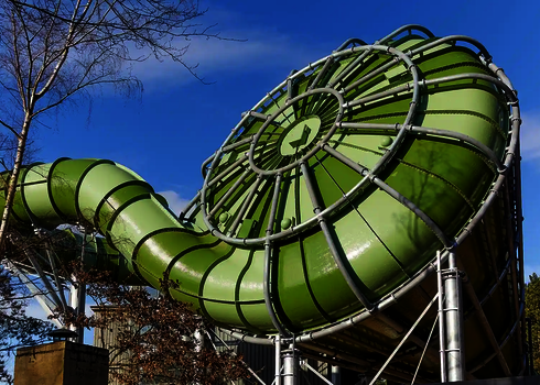 Grüner Cyclone mit auffälliger Endkappe und angrenzender Röhrenrutsche bei blauem Himmel.