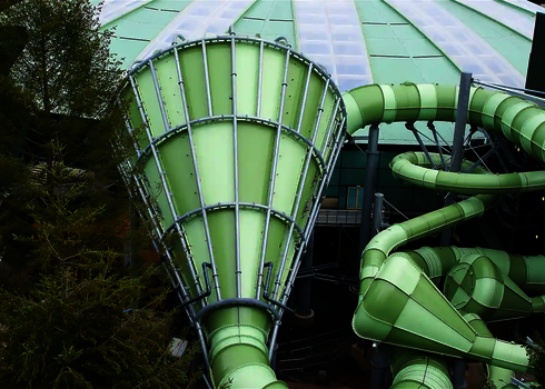 Großer Cyclone in Grün mit markanter Trichterform vor einem runden Dach mit Glasflächen.