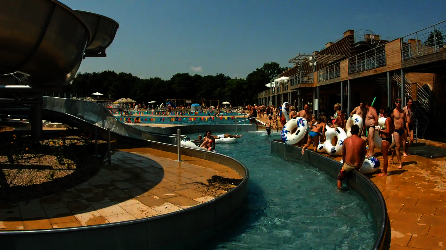Lazy River mit Rutschreifen, Besuchern und Liegeflächen am Beckenrand.