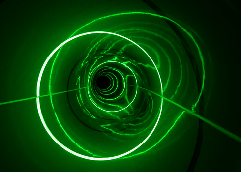 Spiralförmige grüne LED-Ringe leuchten im Inneren einer dunklen Röhrenrutsche.