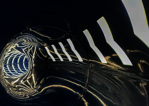 Geschlossene dunkle Wasserrutsche mit glänzenden Lichteffekten.