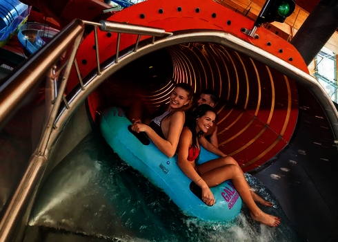 Drei Personen starten auf blauem Reifen in den beleuchteten Family Twister.
