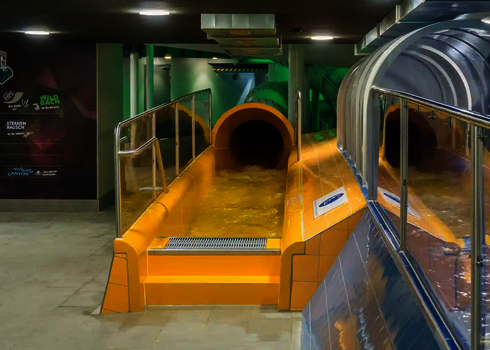 Yellow slide exit with start channel, stainless steel railing and glass side wall.