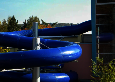 Blaue Röhrenrutsche mit Dämmung spiralförmig um einen Pfeiler gewickelt.