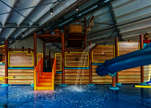 Spielschiff in einem Wasserbecken, mit einer kleinen Treppe, spritzendem Wasser und einer Wasserrutsche des Typs RR900-Kids.