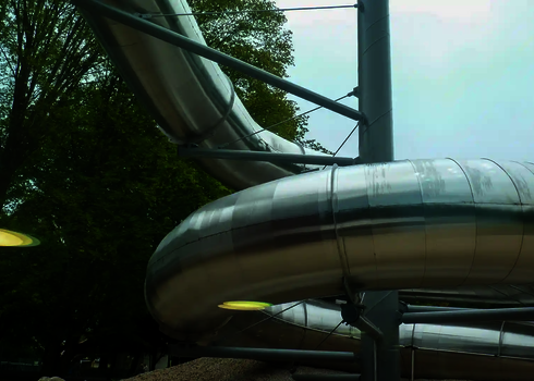 Edelstahlrutsche getragen von Stahlstützen, im Hintergrund Bäume.