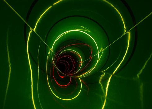 Grüne Rutsche mit LED-Ringen in Gelb und Rot, die leuchtende Spiralen erzeugen.